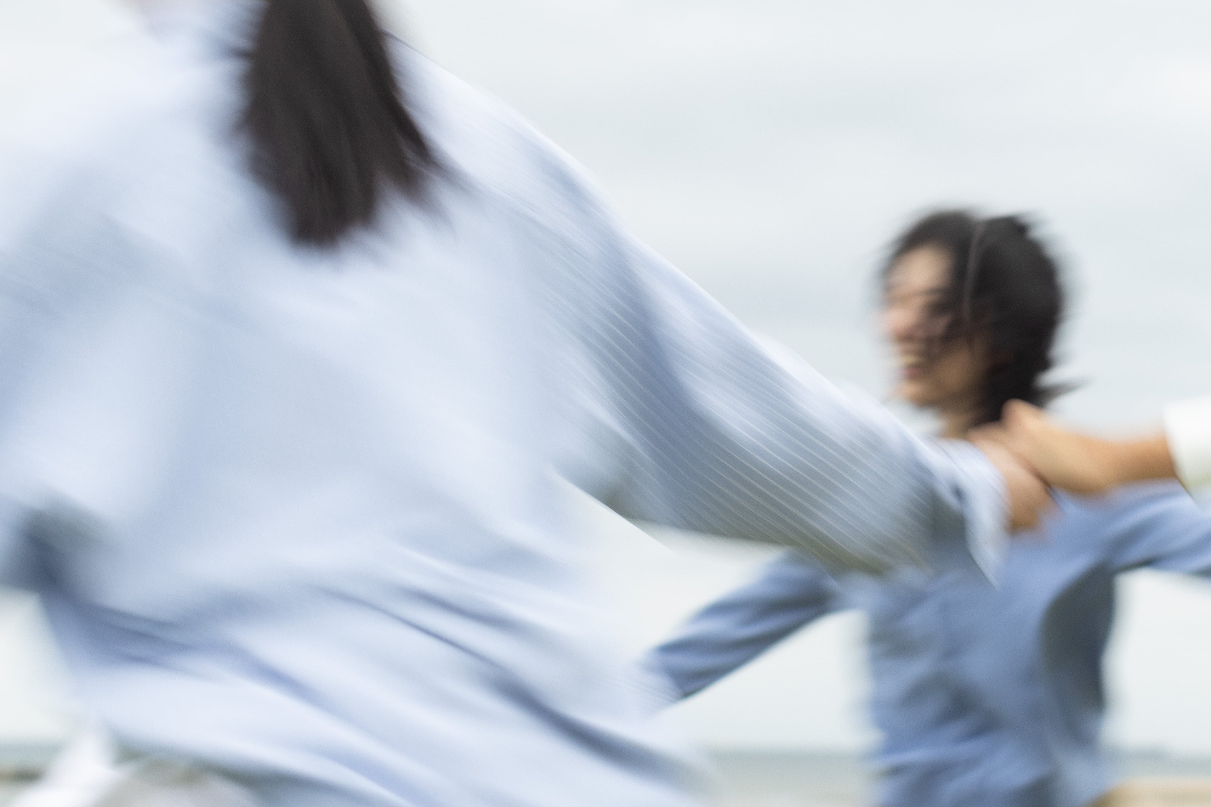 People in motion wearing light blue shirts in a photograph by Osamu Yokonami
